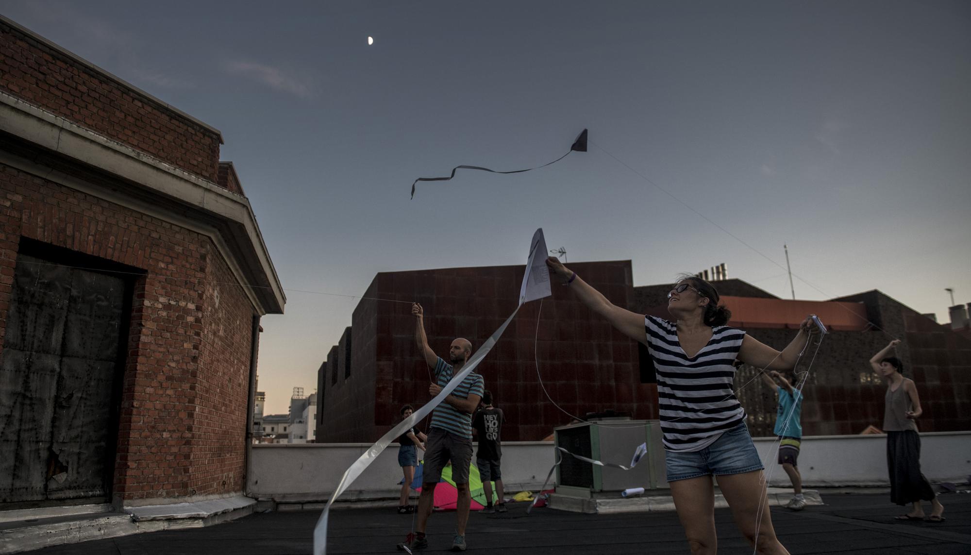 Un grupo de gente volando cometas a la luz del anochecer en la terraza de La Ingobernable